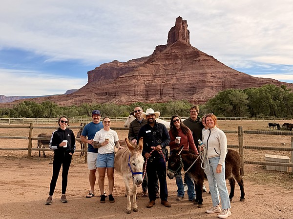 Guests posing with donkeys beneath the red rock Palisade at Gateway Canyons Resort in Gateway, Colorado