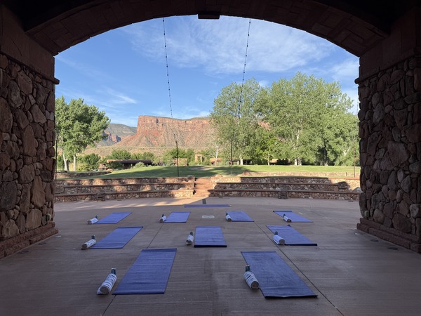 Outdoor yoga mats arranged under a stone arch pavilion with red rock mesa views at Gateway Canyons Resort in Gateway, Colorado