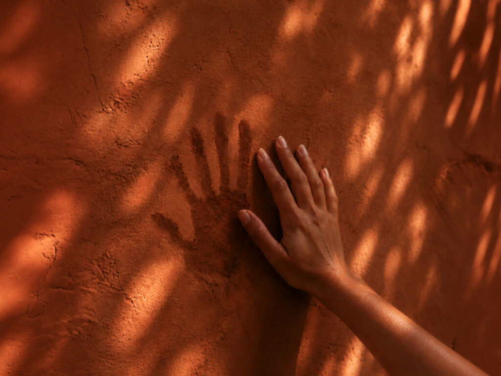 Hand Touching A Clay Wall